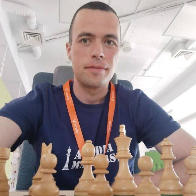 Jordan sitting behind a wooden chess set
